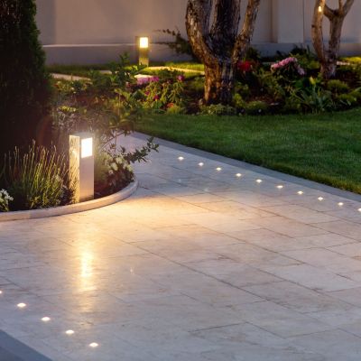 marble tile playground in the night backyard of mansion with flowerbeds and lawn with ground lamp and lighting in the warm light at dusk in the evening.