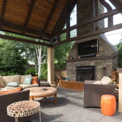 An upscale backyard terrace featuring perennials and with a custom designed shelter and fireplace.
